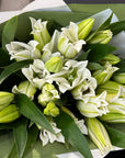 Bouquet of white Oriental Lillies with green leaves and gift wrapped.