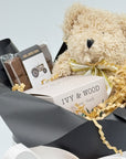 Close Up image of teddy bear, chocolate bar, and candle on light gray background