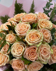 Bouquet of peach-colored roses with green leaves on a pink background