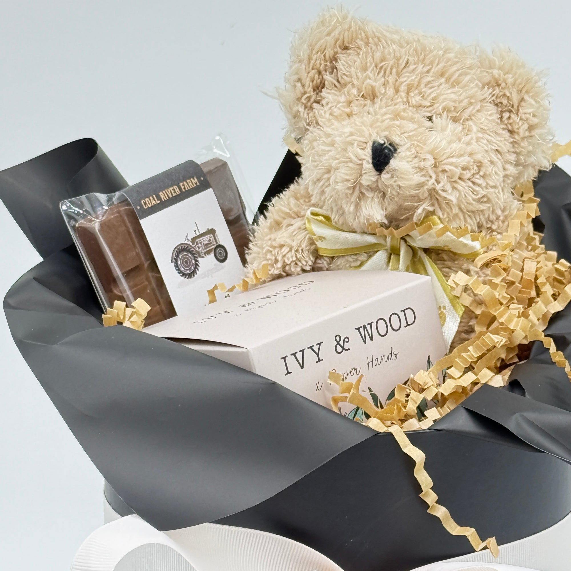 Close Up image of  teddy bear, chocolate bar, and candle on light gray background