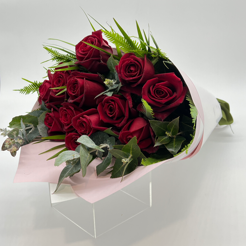 A bouquet of 12 red premium roses with green foliage, elegantly wrapped.
