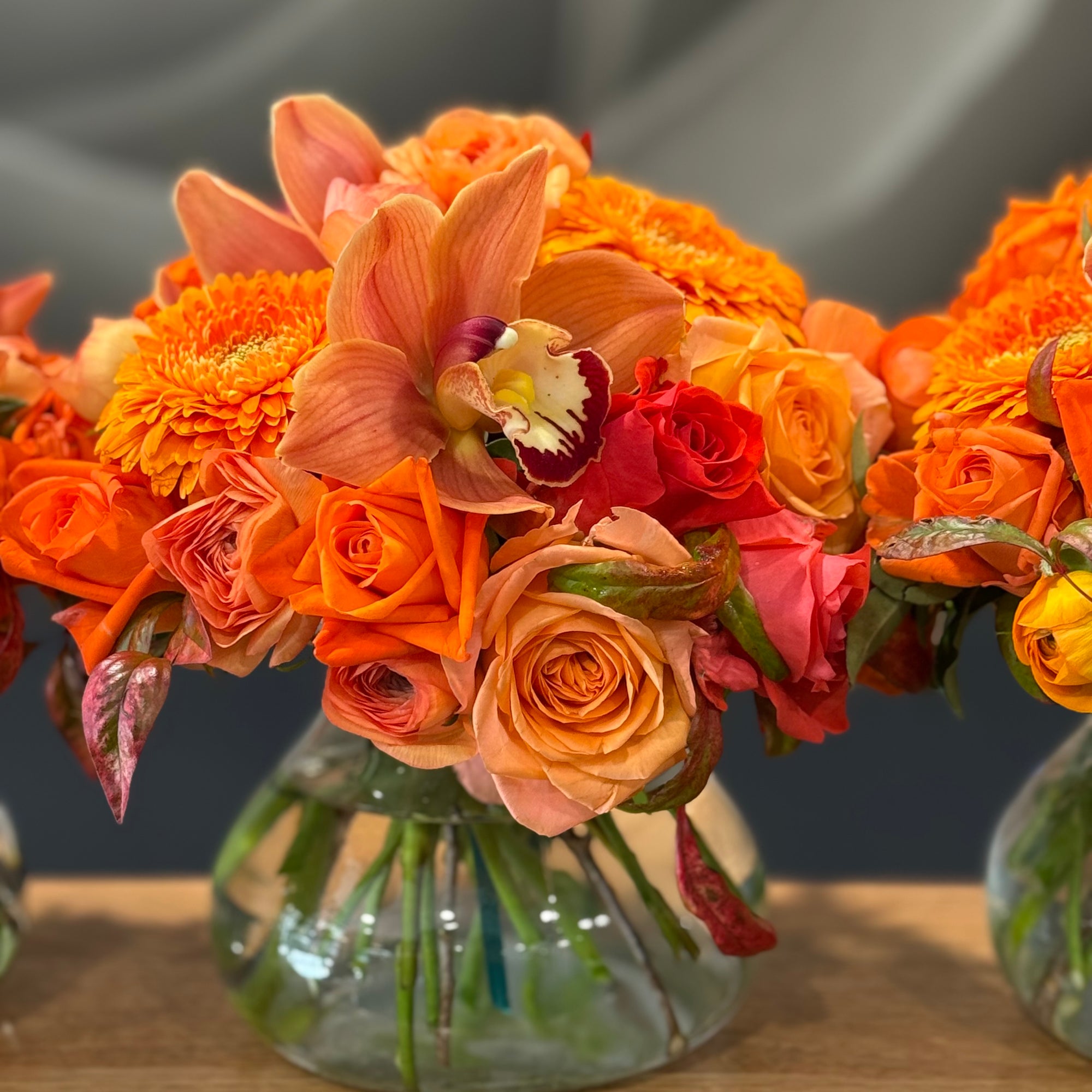 Posy Vase of assorted flowers in organs against a grey background.