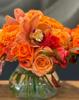 Posy Vase of assorted flowers in organs against a grey background.