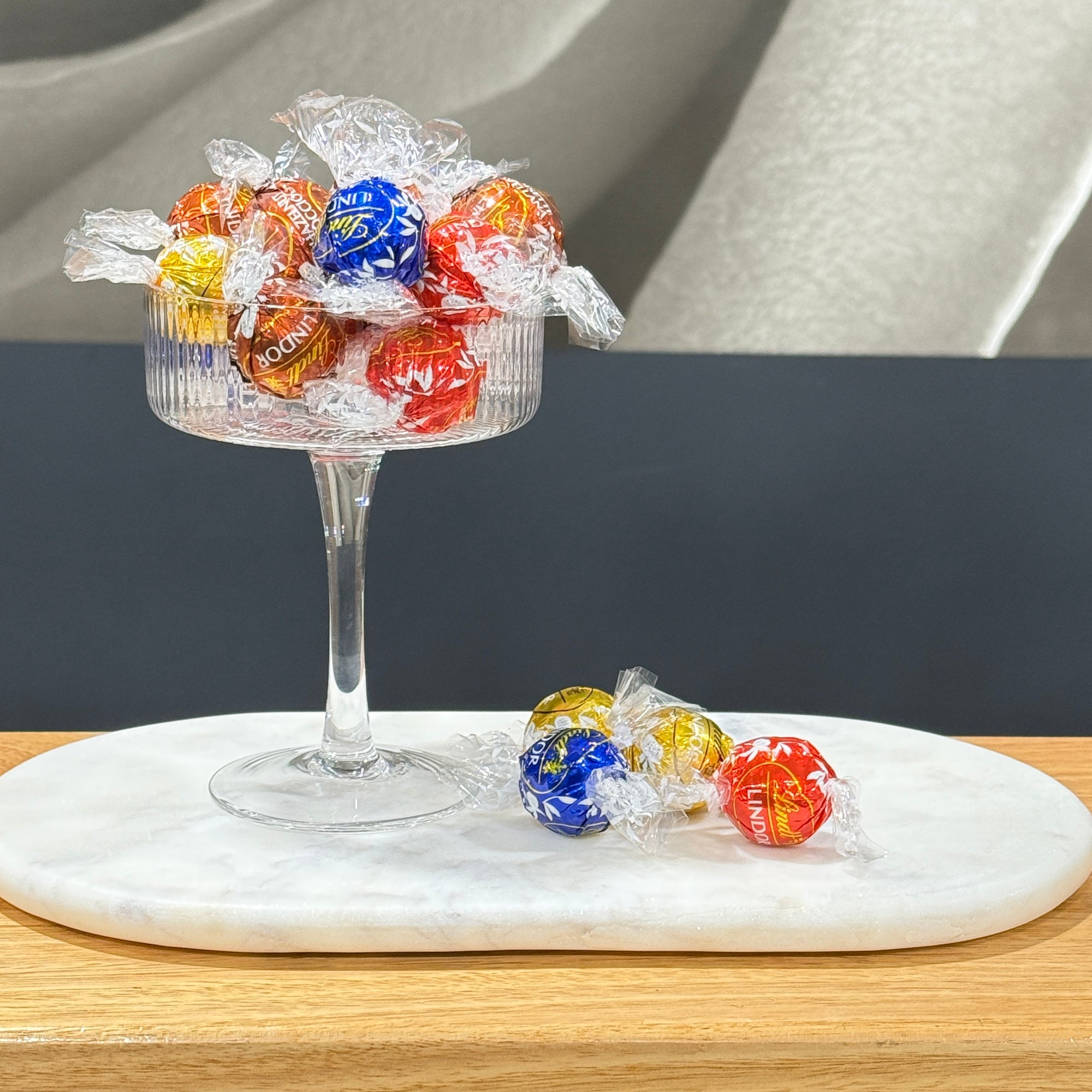 Lindt Lindor Chocolate balls on a white marble plate on a wooden bench.