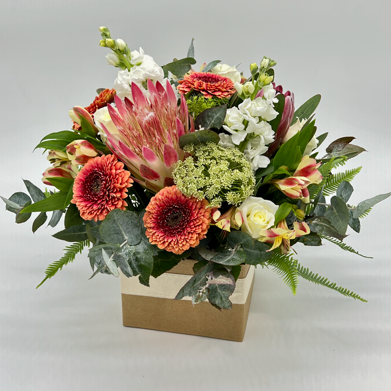 A medium-sized box arrangement of assorted flowers including shades of red, pink, white, and green.