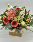 A medium-sized box arrangement of assorted flowers including shades of red, pink, white, and green.