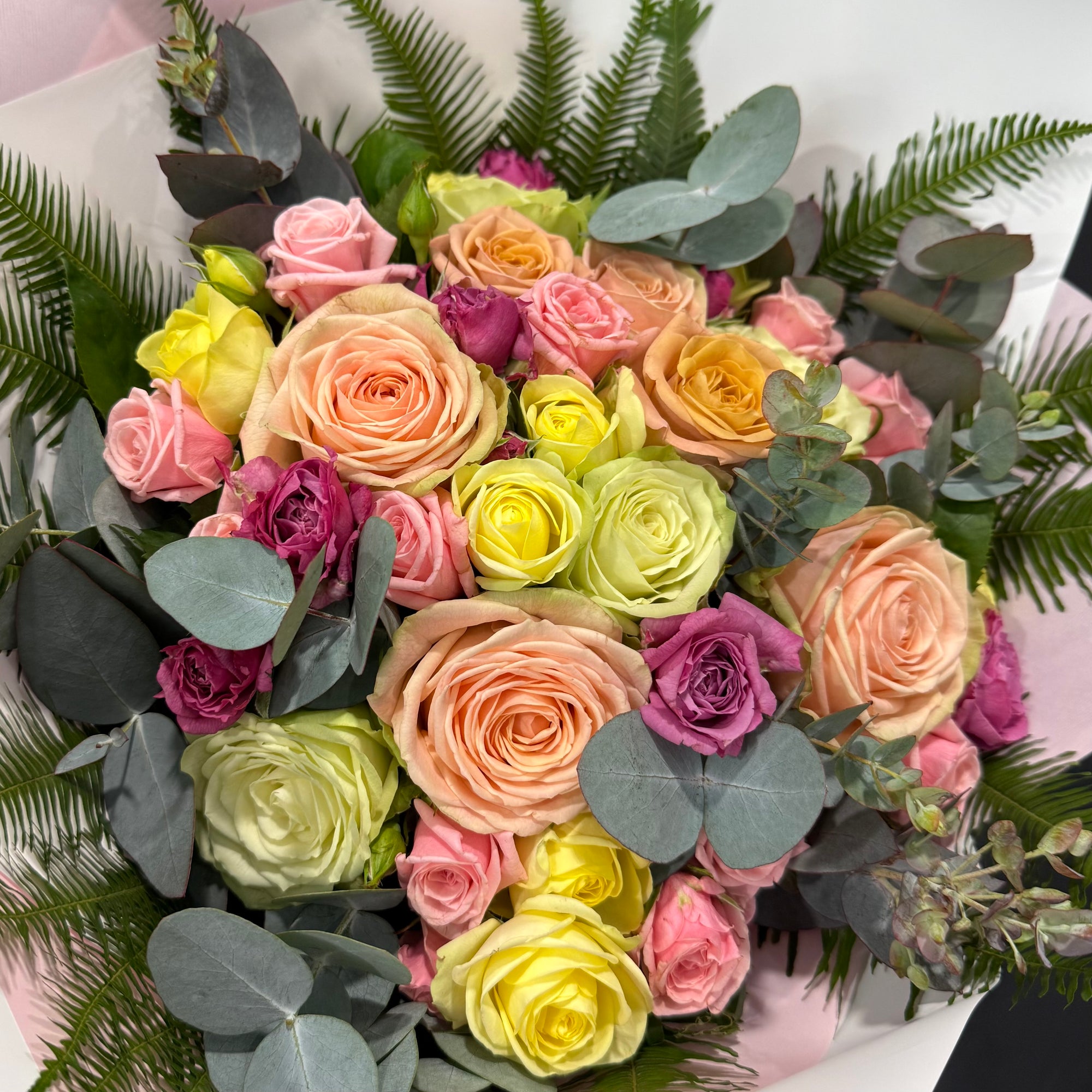 Bouquet of colorful roses with eucalyptus leaves on a white background