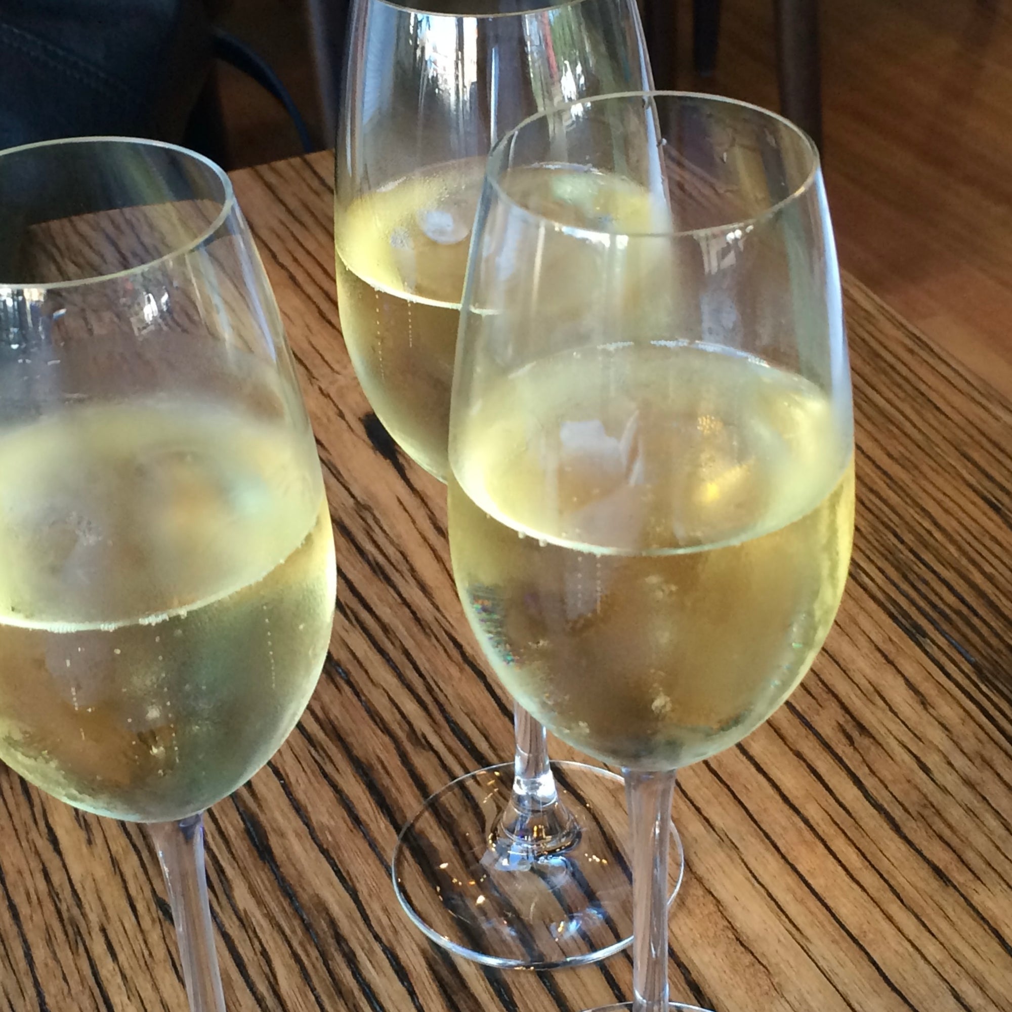 Three wine glasses filled with sparkling wine on a wooden table